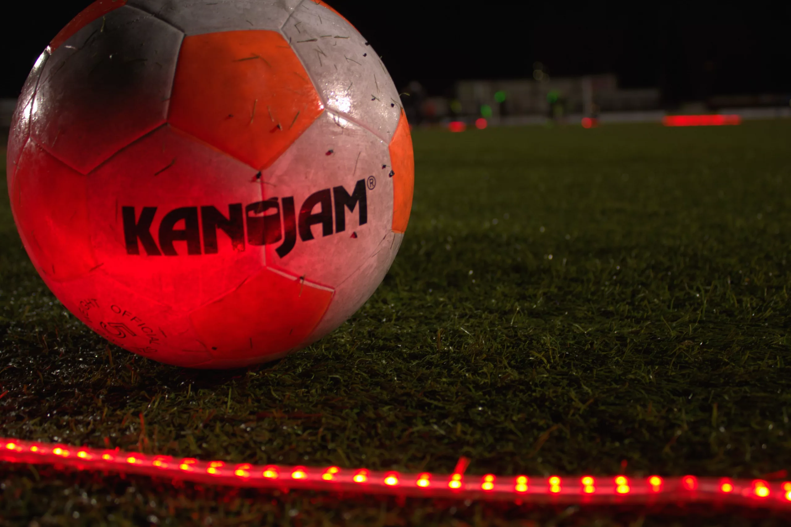 Foto van een LED voetbal bal met rode LED strips op een voetbalveld led voetbal toernooi led voetbal begeleid