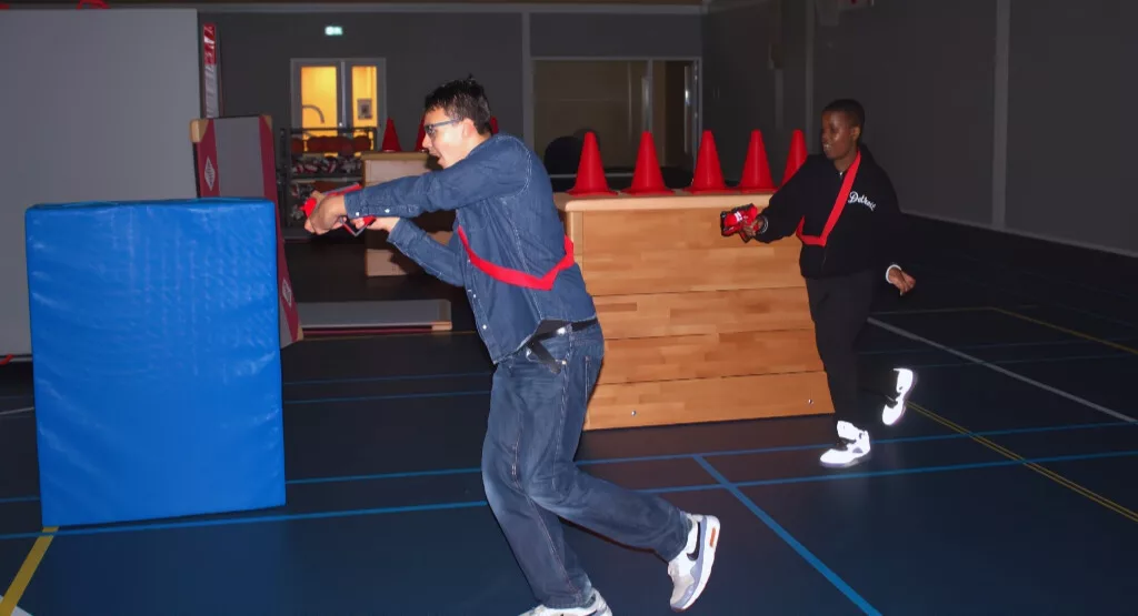 Jongen aan het lasergamen in de gymzaal van een middelbare school